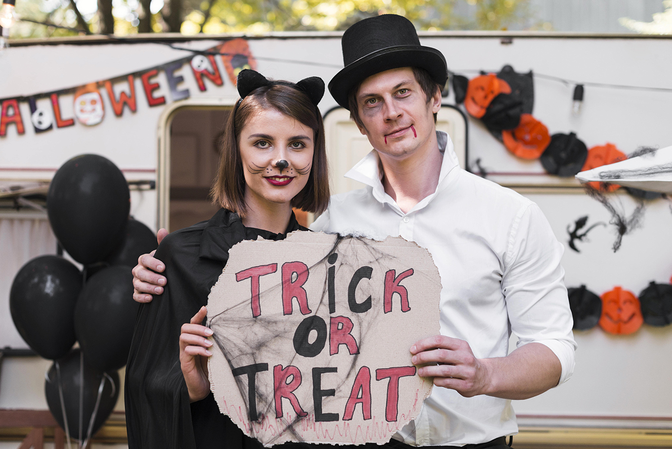 smiley-couple-holding-halloween-sign-min