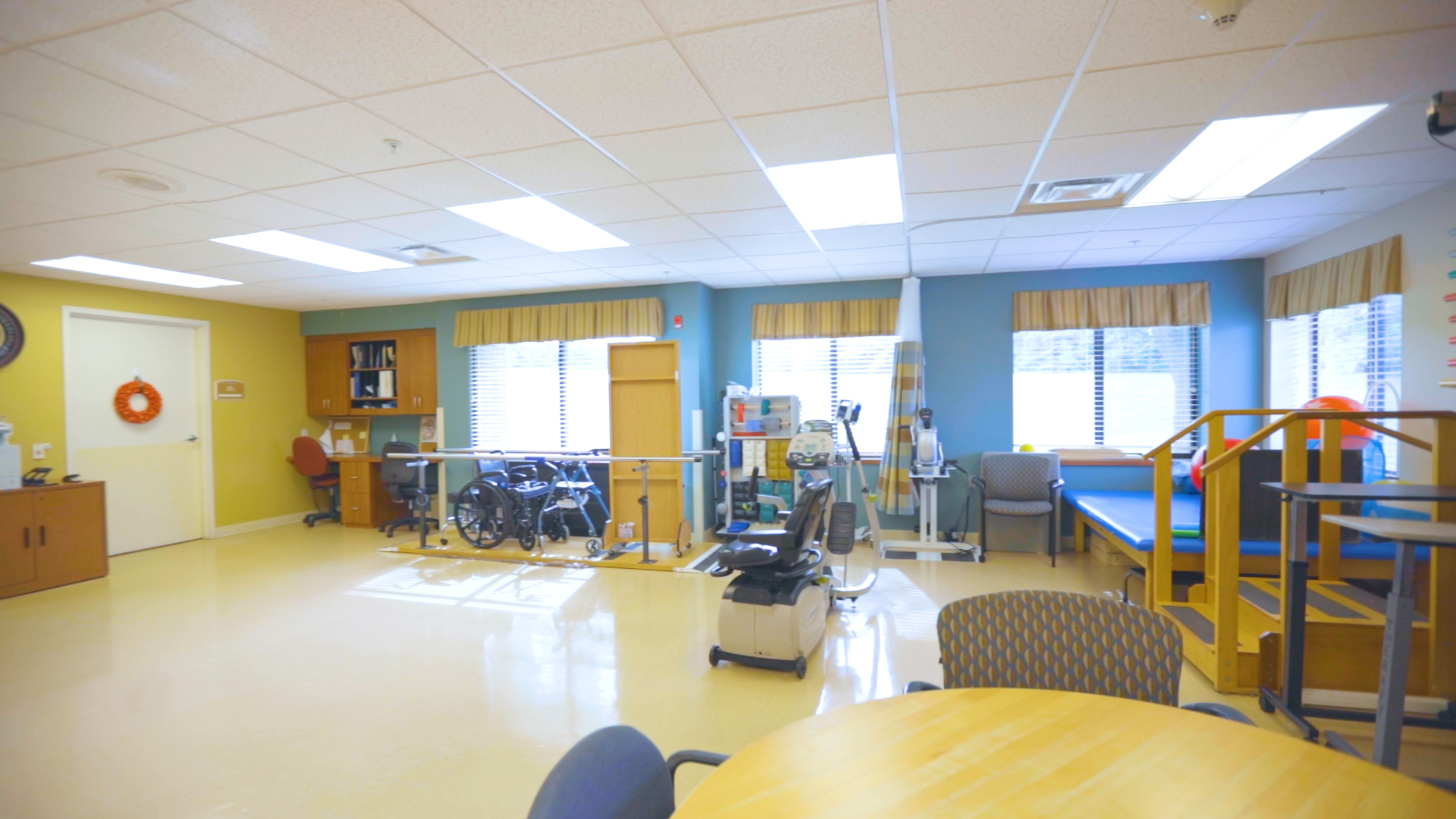 Therapy Room with therapy equipment. Four windows in the background with daylight shining through.